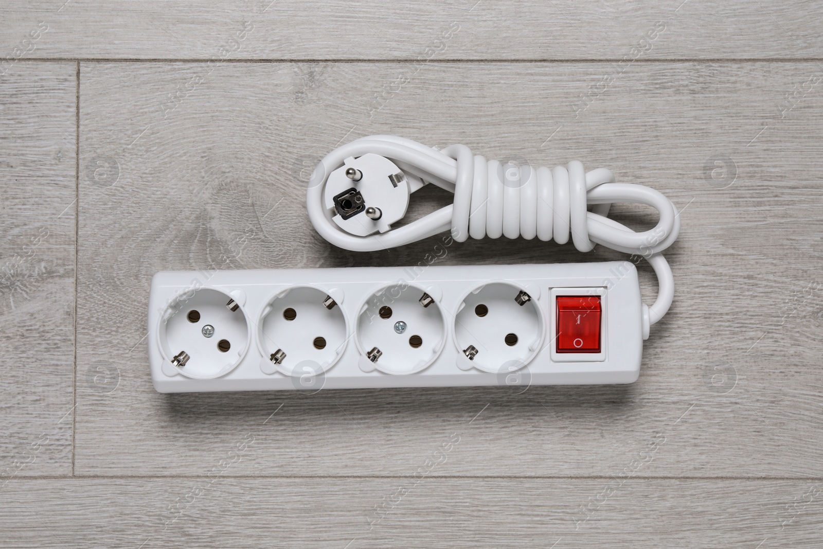 Photo of Power strip on wooden floor, top view. Electrician's equipment