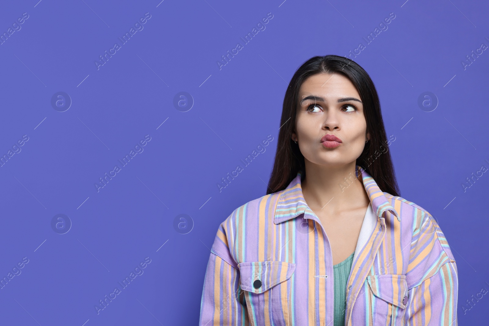 Photo of Beautiful young woman giving kiss on purple background. Space for text