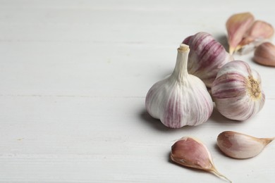 Photo of Fresh organic garlic on white wooden table. Space for text