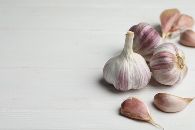 Fresh organic garlic on white wooden table. Space for text