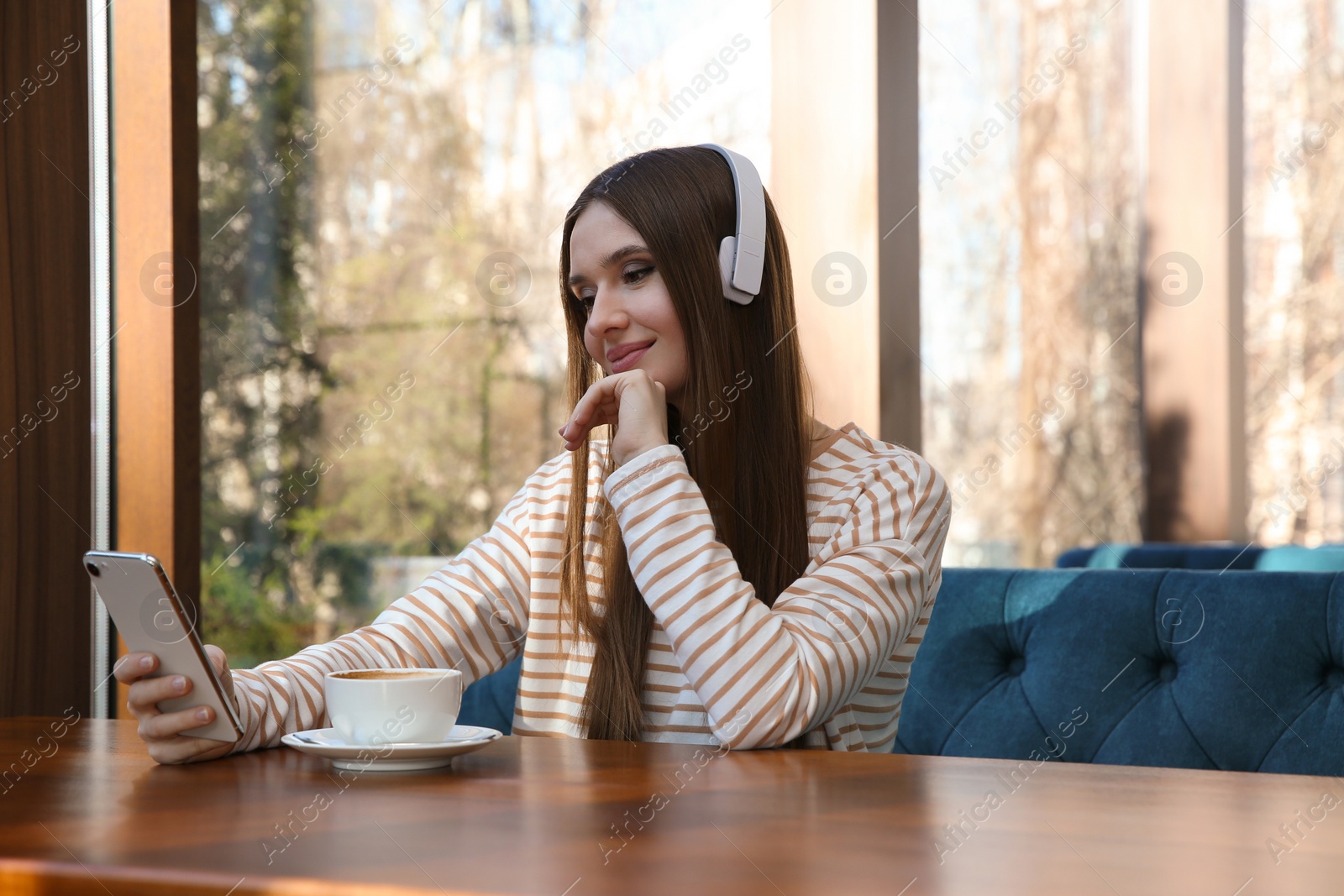 Photo of Woman listening to audiobook at table in cafe