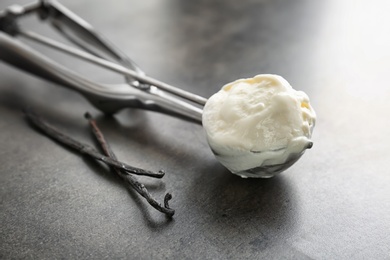 Photo of Scoop with tasty vanilla ice cream on grey background