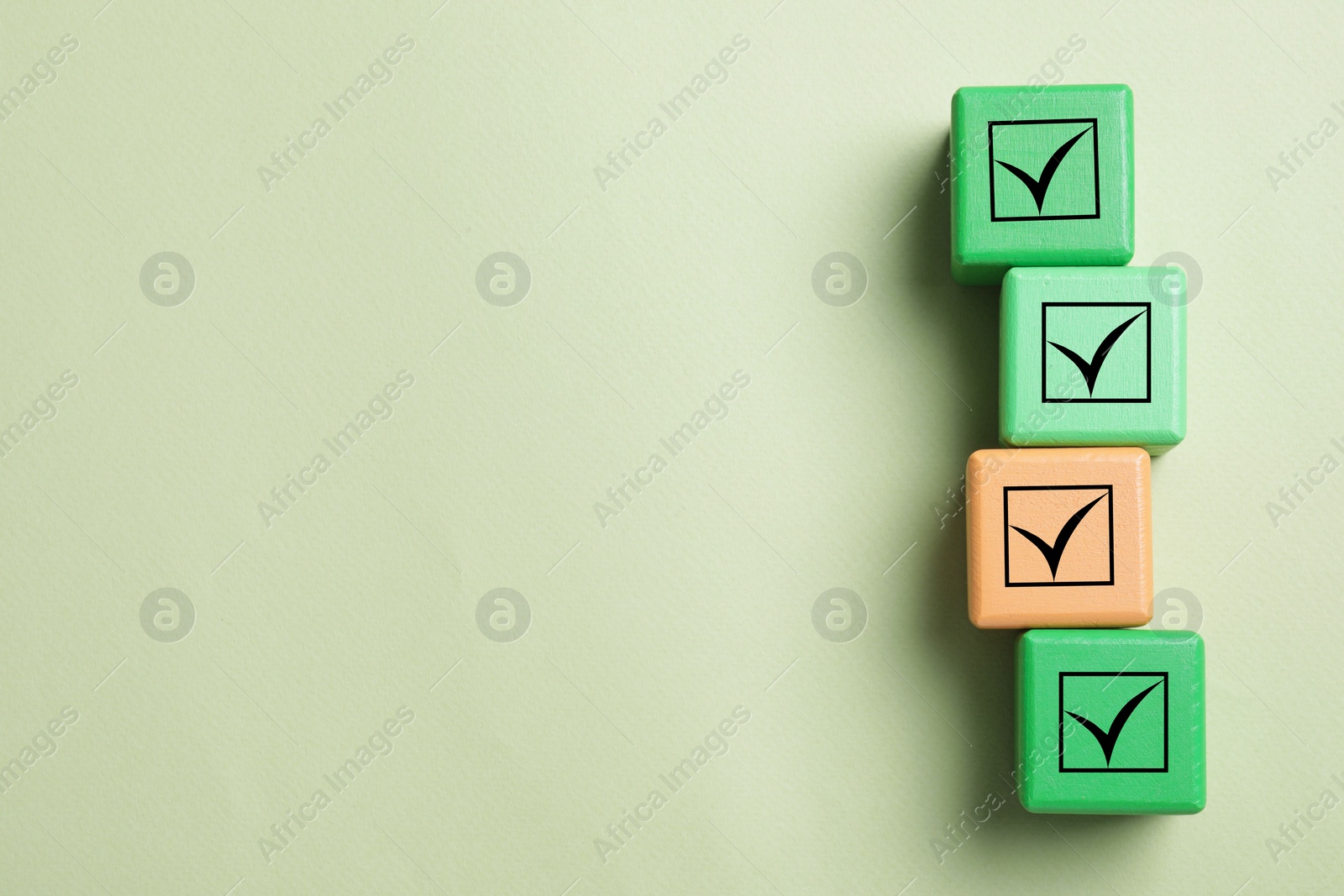 Image of Cubes with check marks on light olive color background, flat lay. Space for text