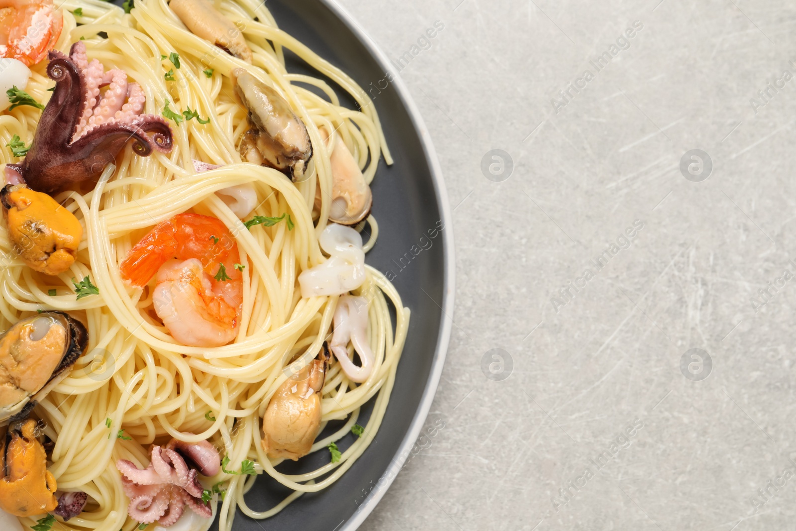 Photo of Delicious pasta with sea food on grey table, top view. Space for text