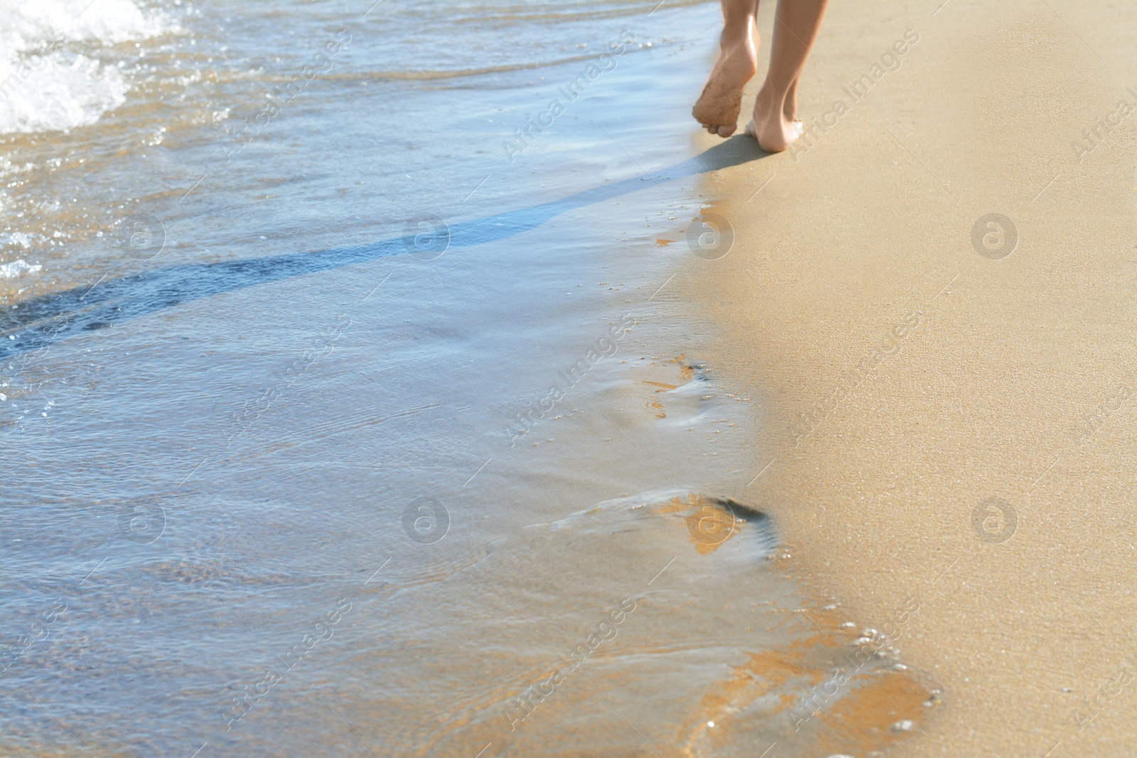 Photo of Woman walking on sandy beach near sea, closeup. Space for text