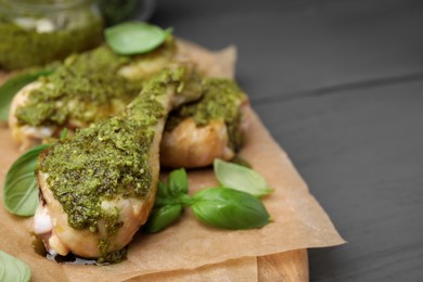 Delicious fried chicken drumsticks with pesto sauce and basil on gray table, closeup. Space for text