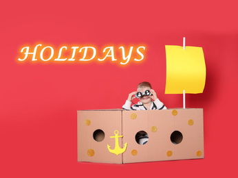Image of School holidays. Cute little child playing with cardboard ship near red wall