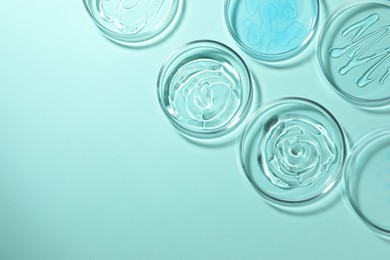 Photo of Petri dishes with liquids on turquoise background, flat lay. Space for text