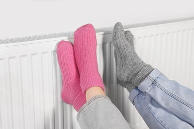 Photo of People warming feet near heating radiator, closeup