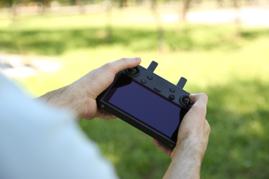 Man holding new modern drone controller outdoors, closeup of hands