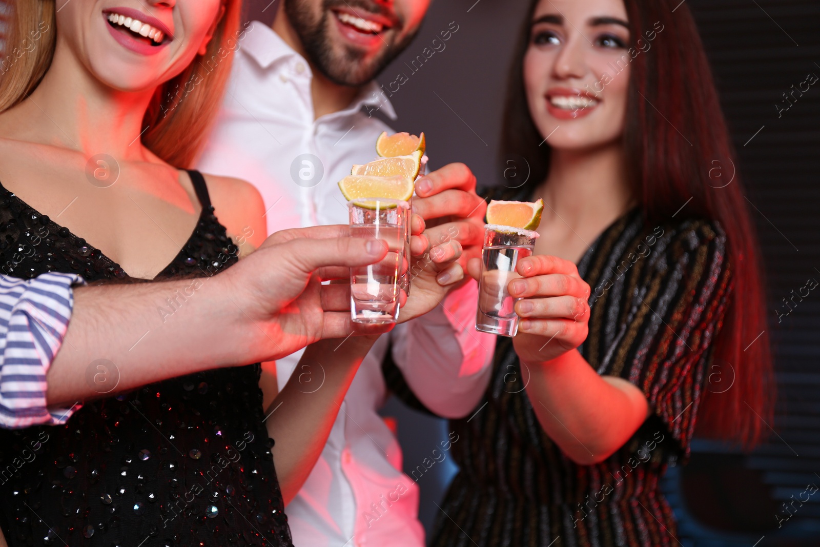 Photo of Young people toasting with Mexican Tequila shots in bar, closeup