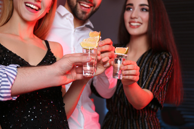 Photo of Young people toasting with Mexican Tequila shots in bar, closeup