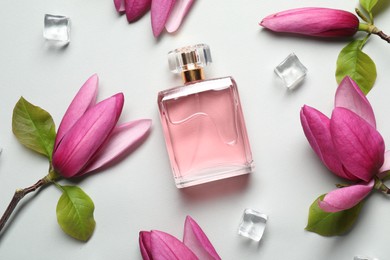 Photo of Beautiful pink magnolia flowers, bottle of perfume and ice cubes on light grey background, flat lay