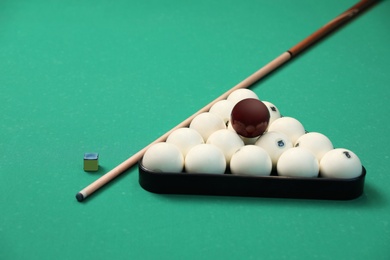 Photo of Billiard balls in triangle rack, cue and chalk on table