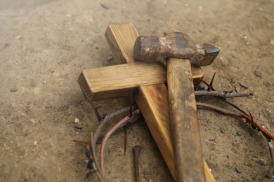 Crown of thorns, wooden cross and hammer on ground. Easter attributes
