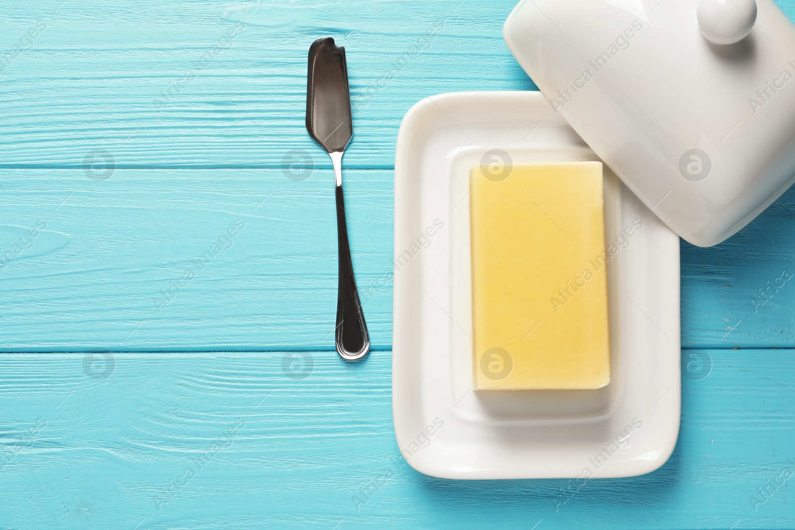 Photo of Dish with fresh butter and knife on wooden background, top view. Space for text