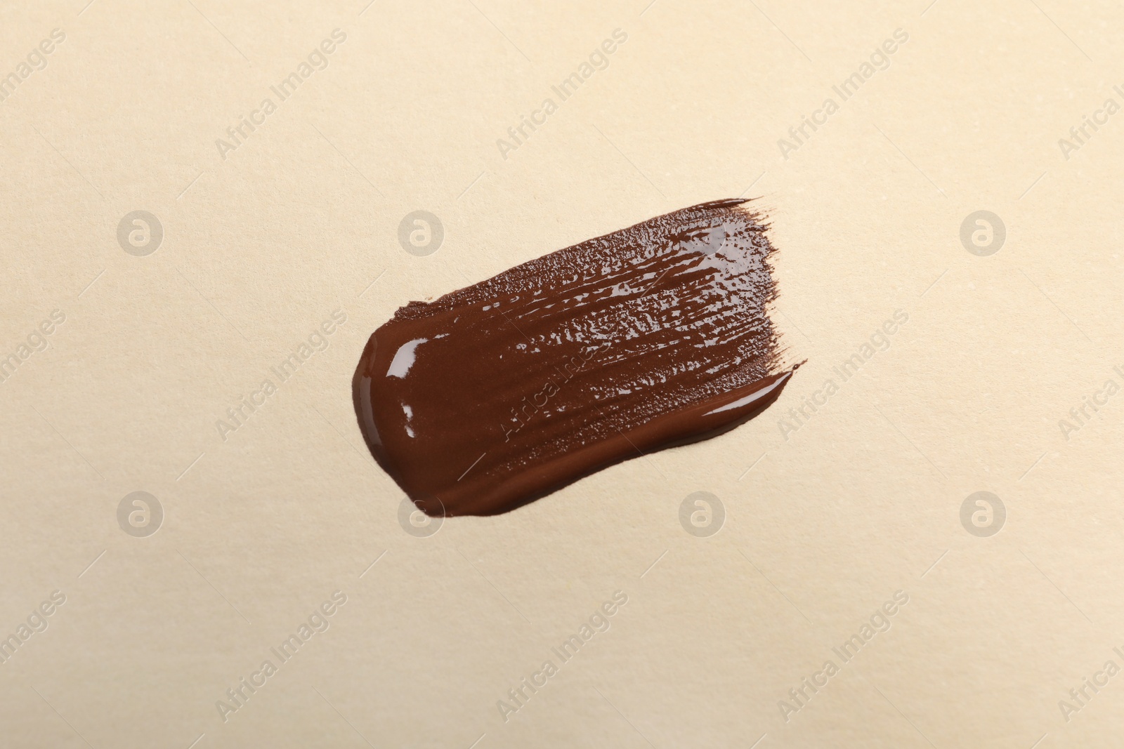 Photo of Smear of skin foundation on beige background, top view