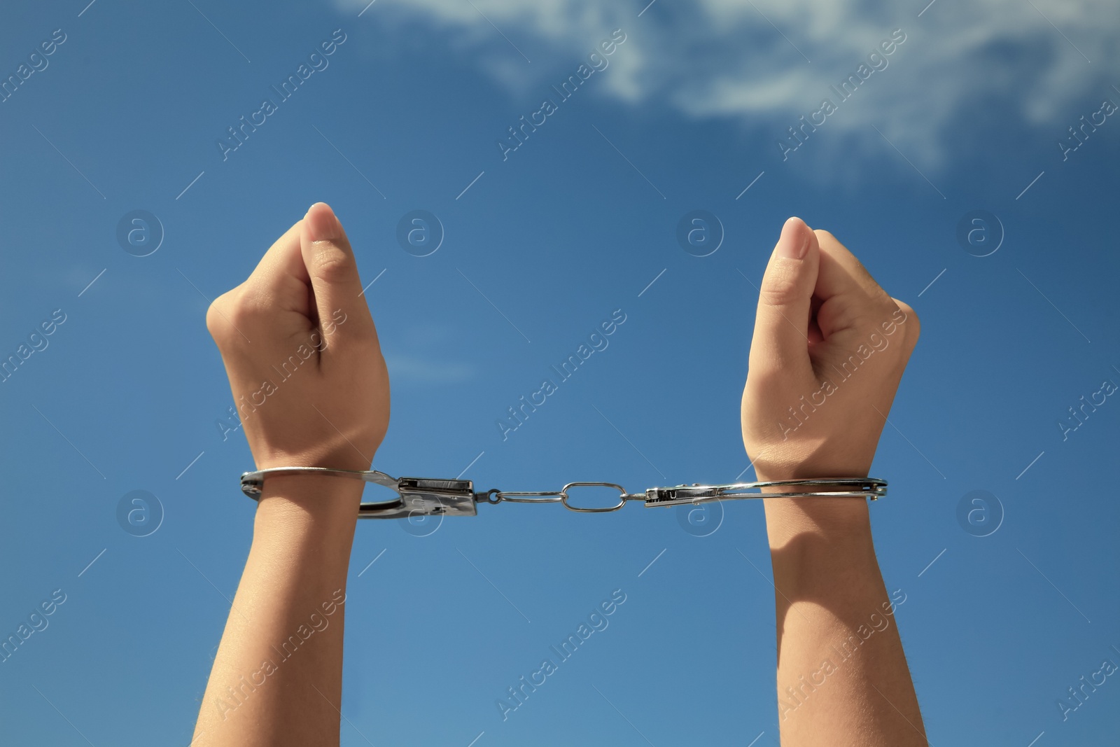 Photo of Woman in handcuffs against blue sky, closeup