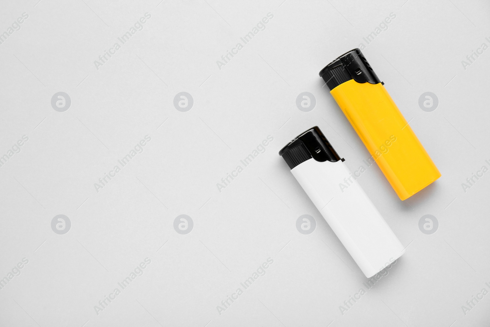 Photo of Stylish small pocket lighters on white background, flat lay. Space for text