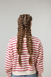 Photo of Woman with braided hair on grey background, back view