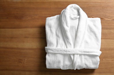 Photo of Clean folded bathrobe on wooden background, top view