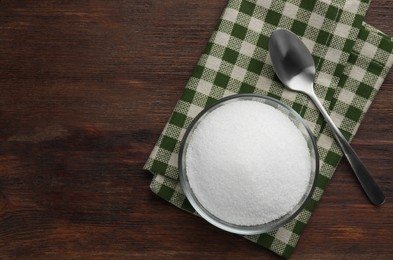 Photo of Granulated sugar in bowl, spoon and napkin on wooden table, top view. Space for text