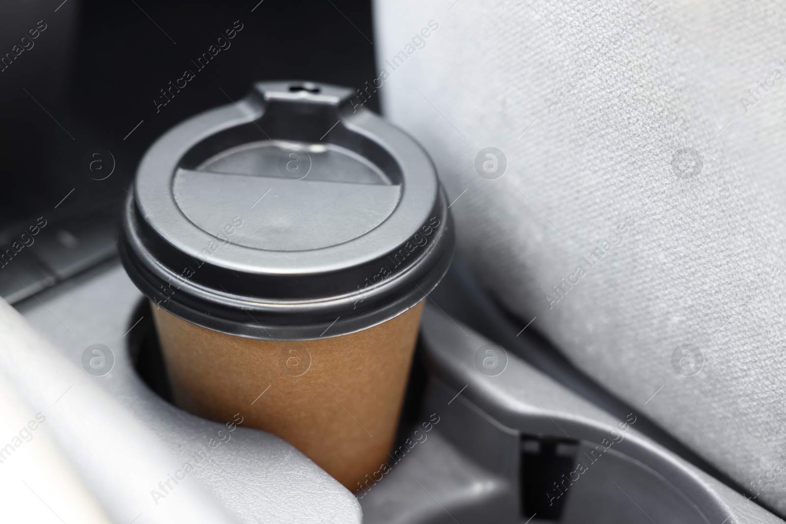 Photo of Coffee to go. Paper cup with tasty drink in holder inside of car, closeup