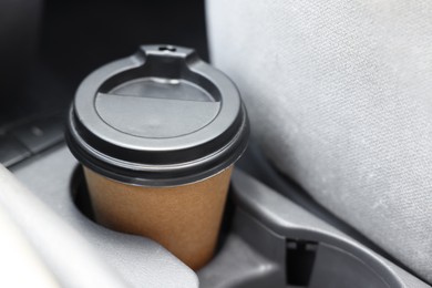 Coffee to go. Paper cup with tasty drink in holder inside of car, closeup