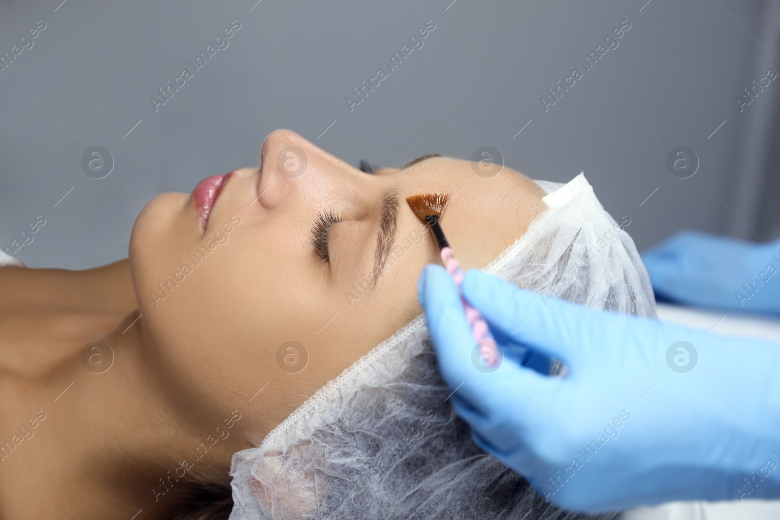 Photo of Cosmetologist applying chemical peel product on client's face in salon