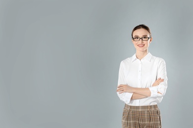 Portrait of young female teacher on grey background. Space for text