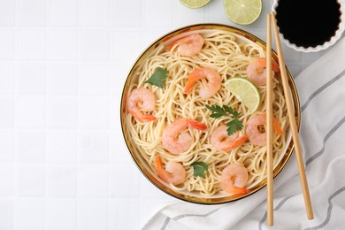 Tasty spaghetti with shrimps, lime, parsley and soy sauce on white tiled table, flat lay. Space for text