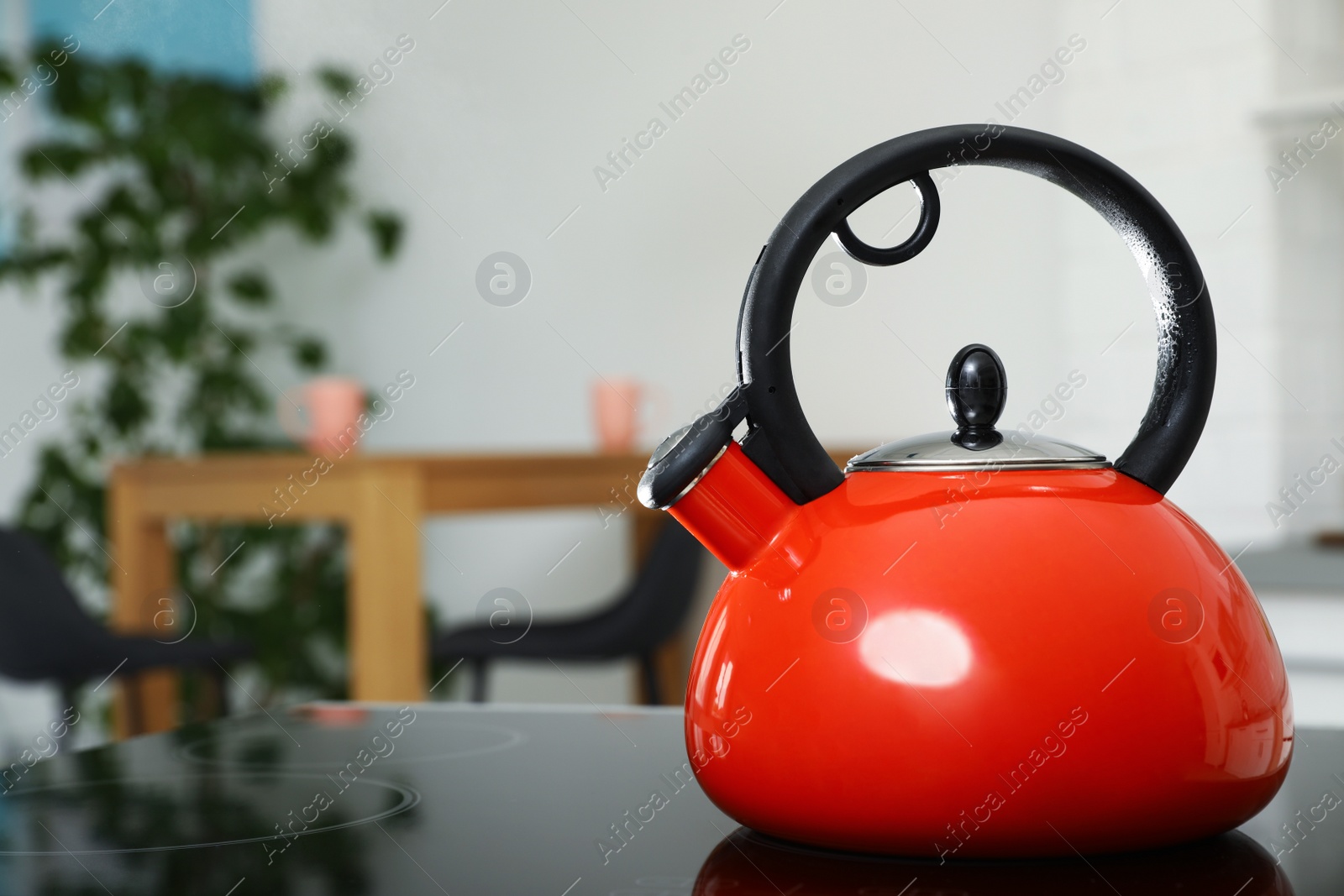 Photo of Modern kettle with whistle on stove in kitchen, space for text