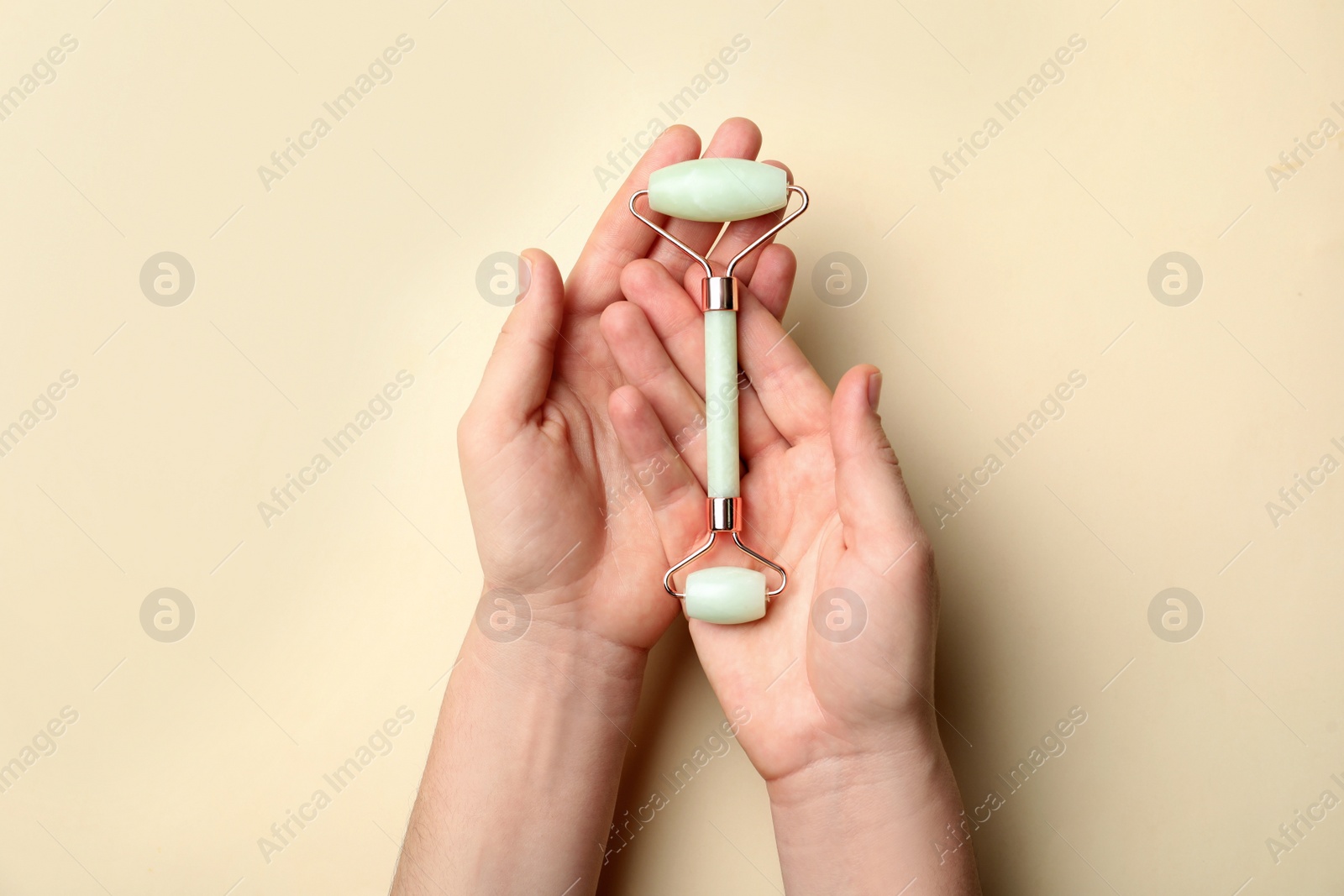 Photo of Woman with natural face roller on beige background, top view