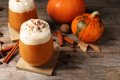 Photo of Glasses with tasty pumpkin spice latte on wooden table