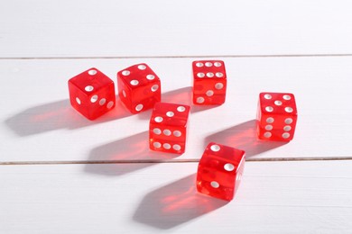 Many red game dices on white wooden table