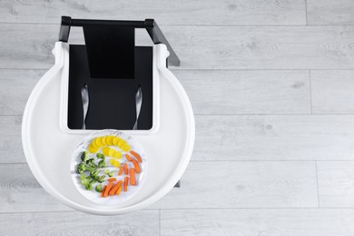 High chair with healthy baby food served on white tray indoors, top view. Space for text