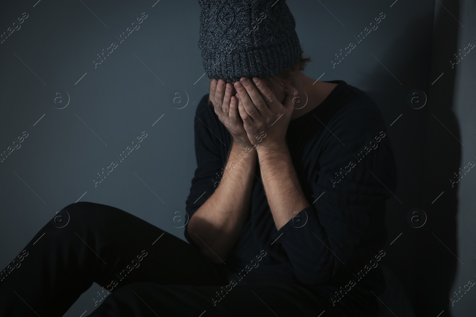 Photo of Male drug addict burying face in his hands on grey background