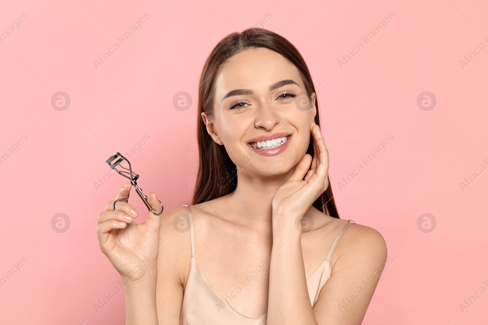 Photo of Woman with eyelash curler on pink background