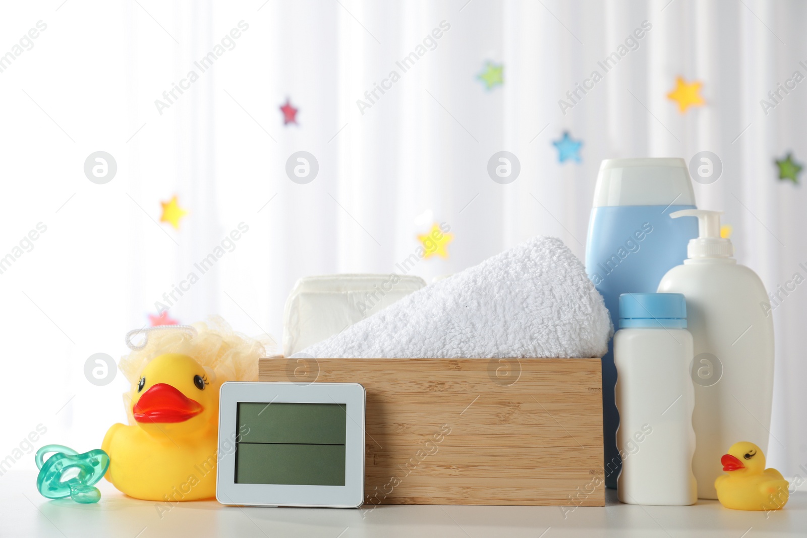 Photo of Towels, rubber ducks, hygrometer and baby care products on white table indoors