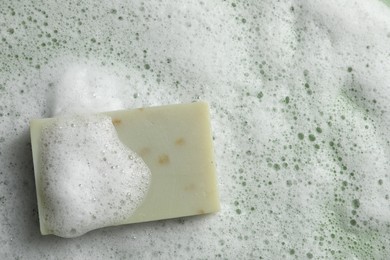 Photo of Soap and fluffy foam on green background, top view. Space for text