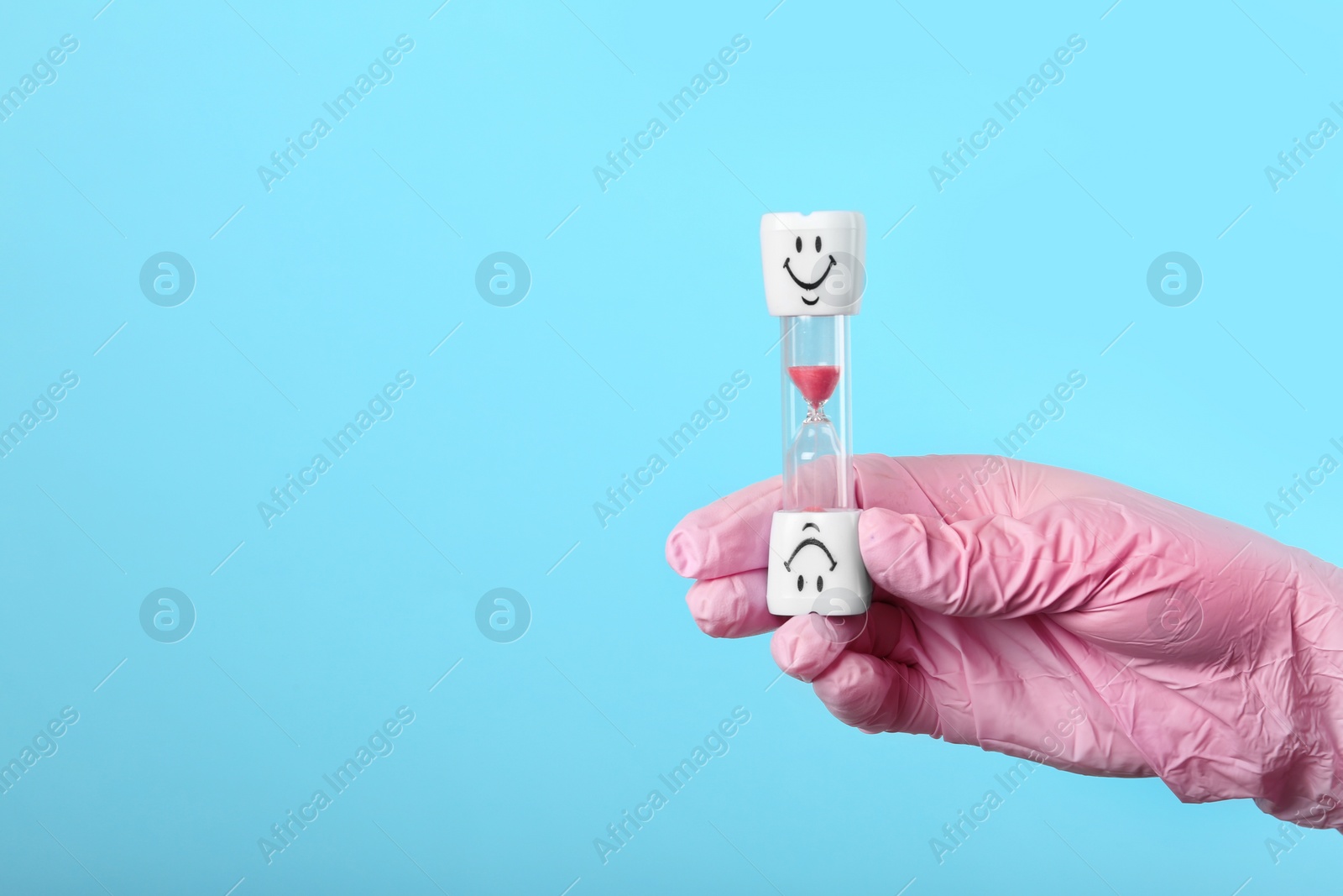 Photo of Dentist holding sand glass on color background, space for text. Brushing teeth time