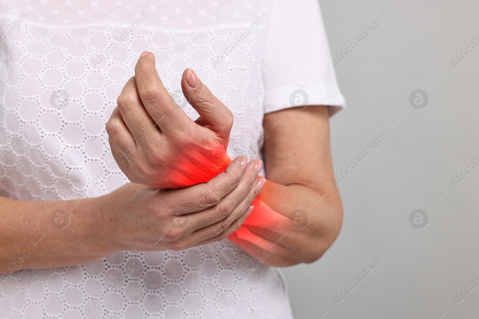 Image of Arthritis symptoms. Woman suffering from pain in her wrist on grey background, closeup. Space for text