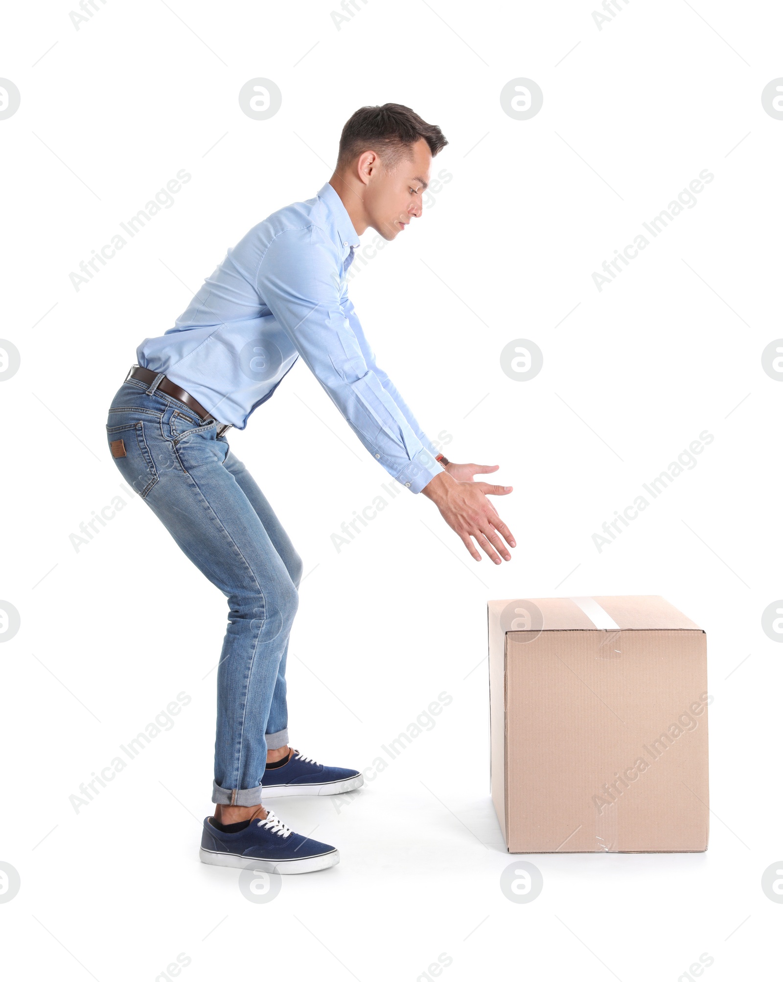 Photo of Full length portrait of young man lifting heavy cardboard box on white background. Posture concept