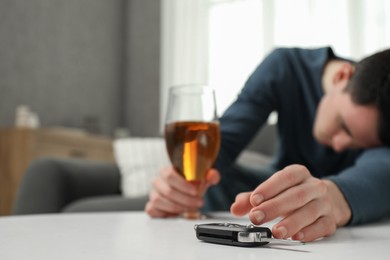 Photo of Drunk man reaching for car keys indoors, selective focus. Space for text