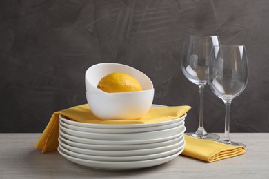 Photo of Set of clean dishware, glasses and lemon on light wooden table