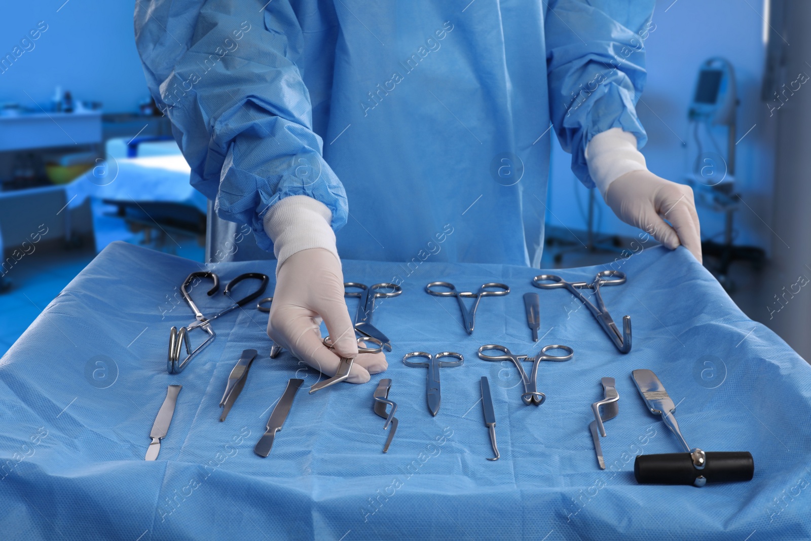 Image of Nurse near table with different surgical instruments in operating room, closeup