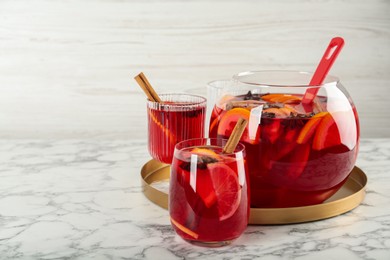 Photo of Glass and bowl of delicious aromatic punch drink on white marble table. Space for text