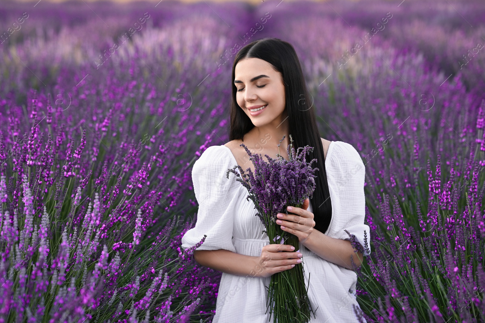 Photo of Beautiful young woman with bouquet in lavender field