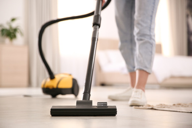 Photo of Young woman using vacuum cleaner at home, closeup