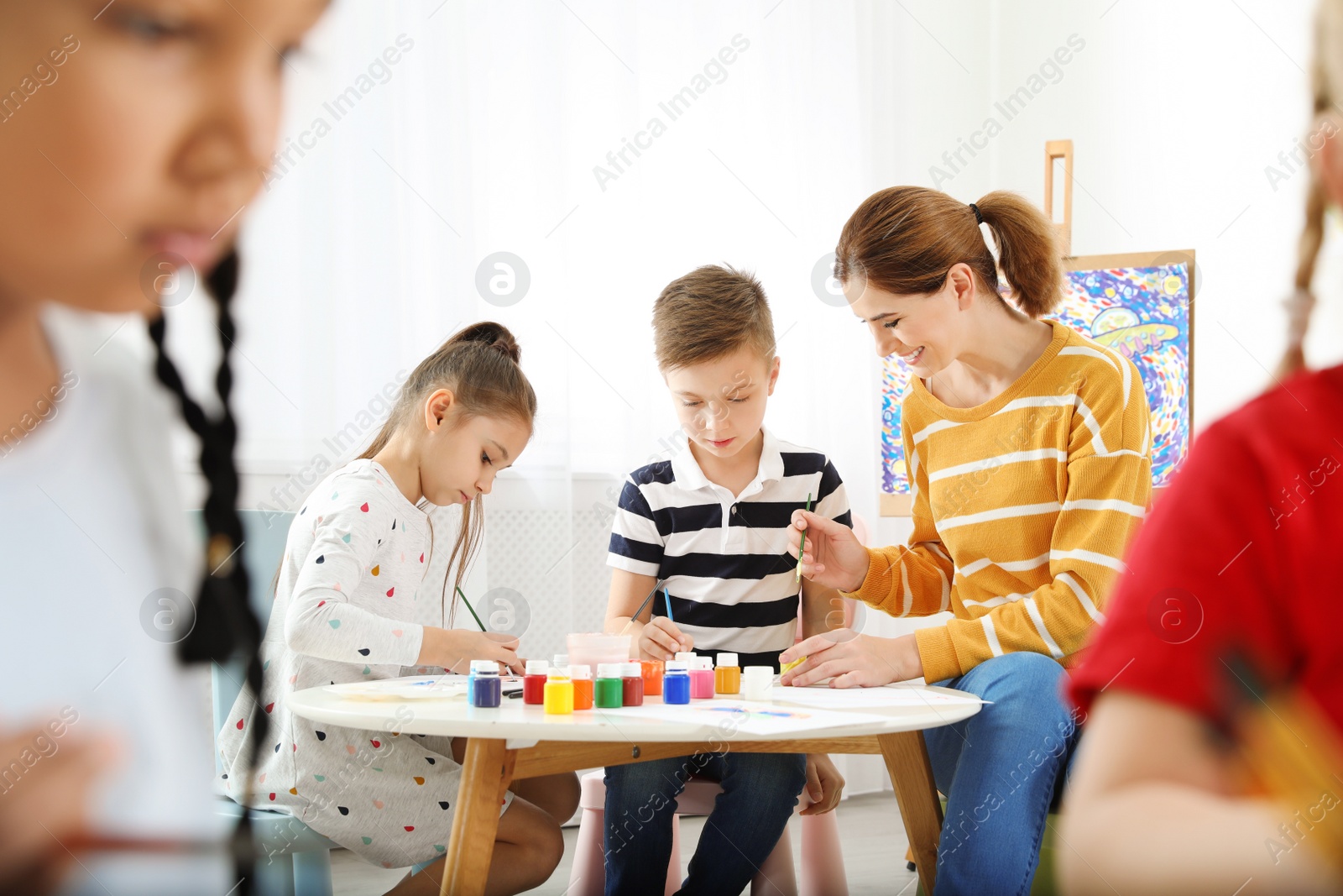 Photo of Children with female teacher at painting lesson indoors